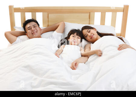 Eine dreiköpfige Familie saß auf dem Bett im Schlafzimmer Stockfoto