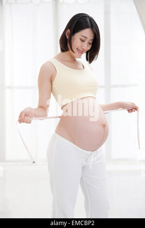 Schwangere Frauen mit einem Lineal Taillenumfang messen Stockfoto