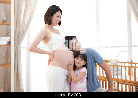 Der junge Vater und Kinder hören den Mutterleib Stockfoto