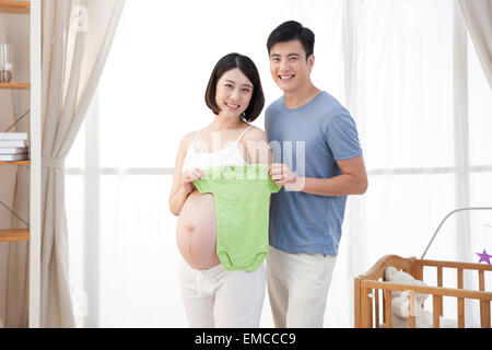 Das glückliche Paar mit einem Baby-Kleidung Stockfoto