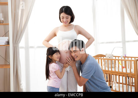 Der junge Vater und Kinder hören den Mutterleib Stockfoto