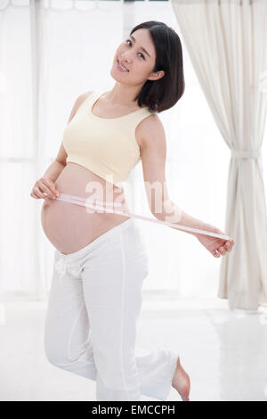 Schwangere Frauen mit einem Lineal Taillenumfang messen Stockfoto