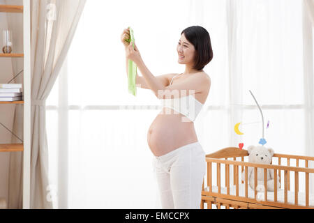 Schwangere Frau mit Baby-Kleidung Stockfoto