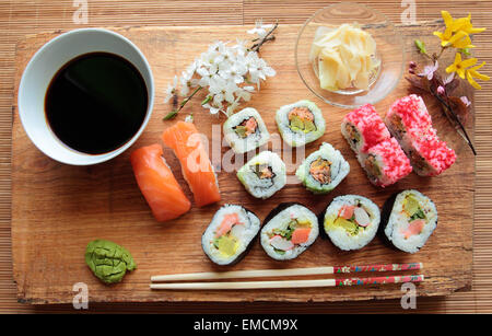 Sushi-Rollen mit Sojasauce und Stäbchen auf Schreibtisch aus Holz Stockfoto