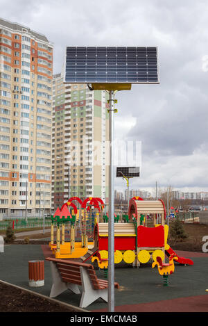 Ein Kinderspielplatz im Hof eines Mehrfamilienhauses mit Sonnenkollektoren Stockfoto