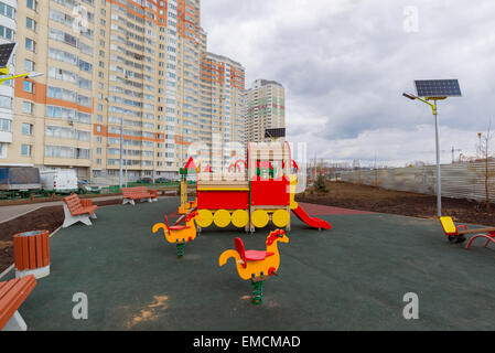 Ein Kinderspielplatz im Hof eines Mehrfamilienhauses mit Sonnenkollektoren Stockfoto