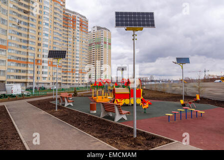 Ein Kinderspielplatz im Hof eines Mehrfamilienhauses mit Sonnenkollektoren Stockfoto