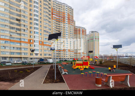Ein Kinderspielplatz im Hof eines Mehrfamilienhauses mit Sonnenkollektoren Stockfoto