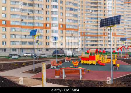 Ein Kinderspielplatz im Hof eines Mehrfamilienhauses mit Sonnenkollektoren Stockfoto