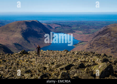 Walker steigt den letzten Teil von Great Gable mit Wast Water in Wasdale als Kulisse im Frühjahr, Lake District, Großbritannien mit Kopierraum Stockfoto