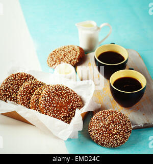 Frische knusprige Schokoladenkekse mit Sesam serviert mit Milch und zwei Morgen Tassen Espresso. Bild mit Instagram Farben abgeschwächt. Stockfoto