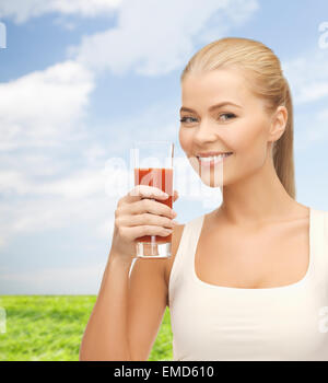 lächelnde Frau halten Glas Tomatensaft Stockfoto