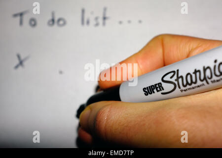 Eine weiße Hand einen Sharpie Stift eine "To do-Liste" auf ein Blatt Papier schreiben. Stockfoto