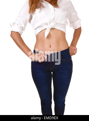 Eine Nahaufnahme Bild der Vorderseite einer jungen Frau in eine weiße Bluse und Jeans, zeigt ihr Bauchnabel, isoliert auf weiss Stockfoto