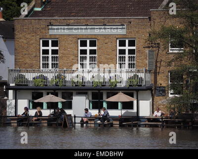 Menschen sitzen vor der Stadt Barge-Pub mit Wasser plätschern um ihre Füße während einer sehr hohen Gezeiten der Themse. Stockfoto