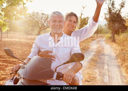 Älteres Paar Reiten Motorroller auf Landstraße Stockfoto