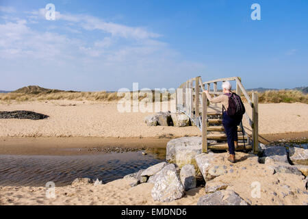 Leitende Person zu Fuß auf Wales Coast Path Fußgängerbrücke über Nicholaston Pille in Oxwich National Nature Reserve auf Gower Halbinsel South Wales UK Stockfoto