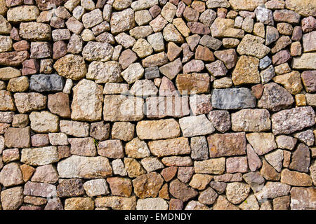 Steinen der verschiedenen Formen, Größen und Farben in einer Trockensteinmauer auf ein Gebäude. UK, Großbritannien Stockfoto