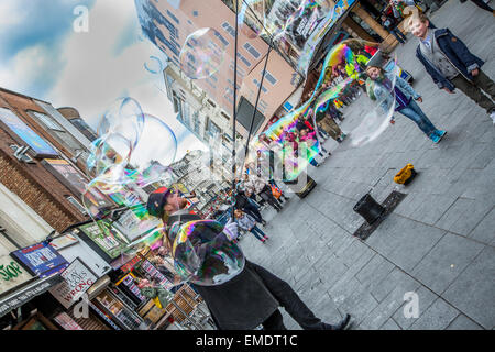 Blase bläst Mann machen riesige bunte Luftblasen in Leicester Square in London Stockfoto