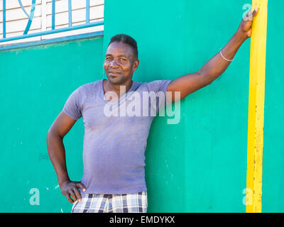 Ein Afro-kubanischen Mann lehnt sich mit seinen Arm gegen bunte Wände von der Außenseite der Nachbarhäuser. Stockfoto