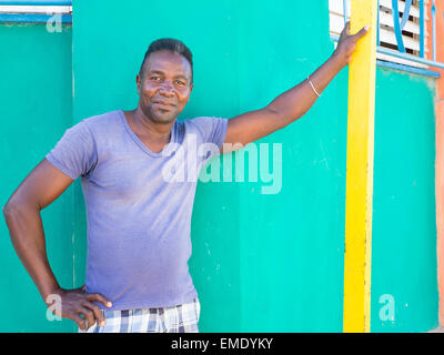 Ein Afro-kubanischen Mann lehnt sich mit seinen Arm gegen bunte Wände von der Außenseite der Nachbarhäuser. Stockfoto