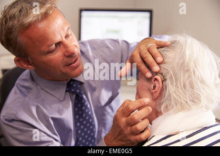 Arzt passend Senior Patientin mit Hörgerät Stockfoto