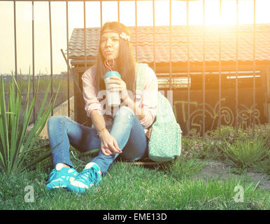 Glückliche junge Latina Teenager Frau hält einen Kaffee zum Mitnehmen Tasse lächelnd. Outdoor Sommer Portrait schöne Teenager-Mädchen Stockfoto