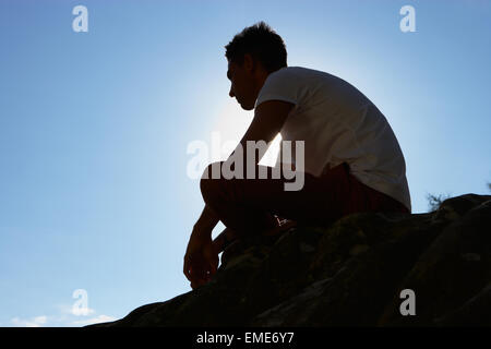 Silhouette der Jüngling sitzt auf Felsen Stockfoto