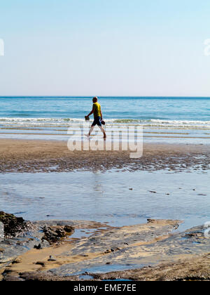 Ein Mann zu Fuß, entlang dem Vorland an einem Strand in der Nähe von Charmouth West Dorset UK mit Wellen, die sanft hinter ihm. Stockfoto