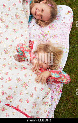 Zwei Mädchen liegen unter Decke auf Campingurlaub Stockfoto