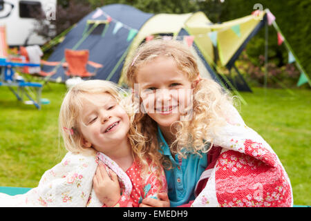 Zwei Mädchen auf Decke während Camping Urlaub mit der Familie entspannen Stockfoto