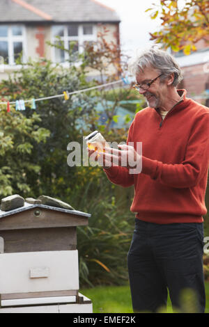 Reifer Mann Honig produziert durch seine eigenen Bienen zu betrachten Stockfoto