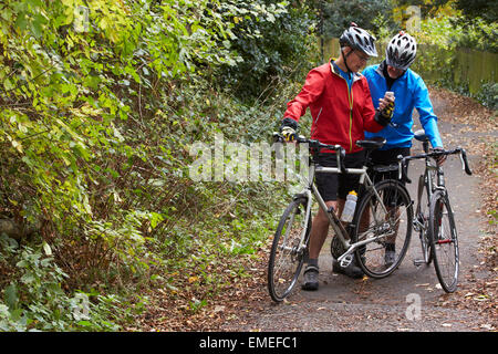 Zwei Reife männliche Radfahrer auf Fahrt Blick auf Handy-App Stockfoto