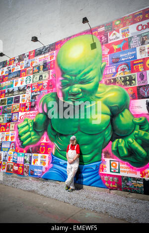 Renommierte Straßenkünstler Ron English posiert vor seinem neuen Bowery Wandbild in Soho in New York Samstag, 18. April 2015. Englisch Arbeit parodiert und kritisiert Konsumismus und es ist sein erstes öffentliches Werk in mehr als einem Jahr. Der rekonstruierte Raum, kuratiert von Jeffrey Deitch, ist berühmt für Hosting-Wandbilder von Graffiti-Künstlern, vor allem Keith Haring. (© Richard B. Levine) Stockfoto