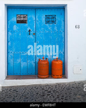 Blaue Tür, weiße Wand und Orange Gasflaschen in Frigiliana, Spanien Stockfoto