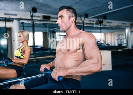 Muskulöser Mann und sportliche Frau Workout auf Trainingssimulator in Crossfit gym Stockfoto