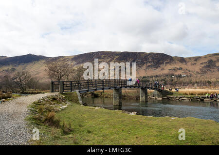 Wanderer auf einer belebten Oster-Wochenende genießen den Blick von der Fußgängerbrücke über den Fluss Derwent Borrowdale, Lake District von Cumbria Stockfoto