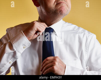 Großaufnahme, männlich in weißem Hemd und blaue Krawatte, er lösen die Krawatte Knoten, gelber Hintergrund Stockfoto