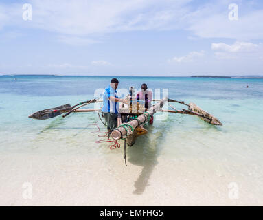 Zwei Fischer mit einem traditionellen Holzboot und Fisch am Strand in Mbudya Insel in Tansania, Afrika. Stockfoto