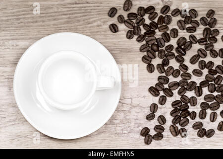 Leere saubere Espressotasse auf Holztisch mit und Kaffeebohnen unscharf Hintergrund von oben Stockfoto