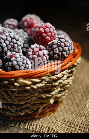 gefrorene Brombeeren im Korb auf altem Holz Stockfoto