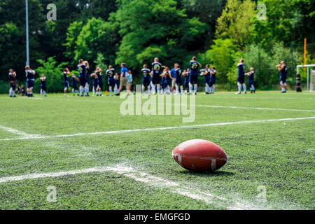 Amerikanischer Fußball auf Feld mit Team im Hintergrund Stockfoto