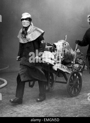 Fleisch-Träger geweitermacht mit ihrer Arbeit mit Mund gegen den Rauch abgedeckt, da das Feuer weiter an Smithfield Fleischmarkt. Zwei Feuerwehrleute wurden getötet, während ein Feuer im Keller der Geflügelmarkt Bekämpfung. Das Feuer, das drei Tage lang gebrannt, war eines der schwierigsten Londoner Feuerwehr hatte seit der Blitz konfrontiert. Station-Offizier Fourt-Wells und Strumpf-Feuerwehrmann starb nach immer in den Kellern des Marktes verloren. Die Tragödie führte zu die Einleitung von Atemschutzgeräten, mit Masken und Sauerstoffflaschen. 23. Januar 1958 Stockfoto