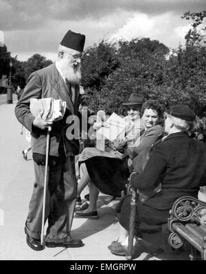 Ein Verkäufer mit religiösen Trakt für Menschen sitzen auf einer Bank in Hampstead Heath, London. 2. November 1954. Stockfoto