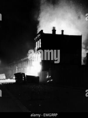 Fahrzeuge liegen auf ihrer Seite in den ausgebrannten Straßen von Brixton ausgebrannt, wie Gebäude nach einer Nacht der Ausschreitungen in Südlondon blaze. 11. April 1981. Stockfoto