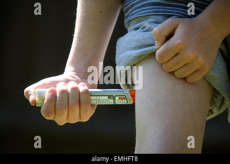 Ein Junge mit einem Epipen an seinem Oberschenkel zeigen was tun bei einem anaphylaktischen Schock Stockfoto