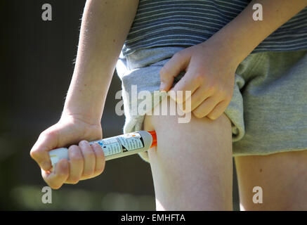 Ein Junge mit einem Epipen an seinem Oberschenkel zeigen was tun bei einem anaphylaktischen Schock Stockfoto