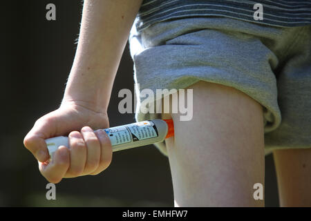 Ein Junge mit einem Epipen an seinem Oberschenkel zeigen was tun bei einem anaphylaktischen Schock Stockfoto