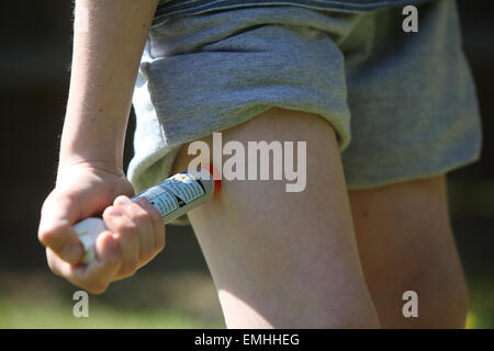 Ein Junge mit einem Epipen an seinem Oberschenkel zeigen was tun bei einem anaphylaktischen Schock Stockfoto