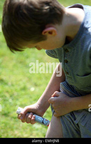 Ein Junge mit einem Epipen an seinem Oberschenkel zeigen was tun bei einem anaphylaktischen Schock Stockfoto